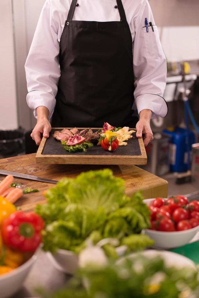 chef femenina sosteniendo un plato de bistec de ternera foto