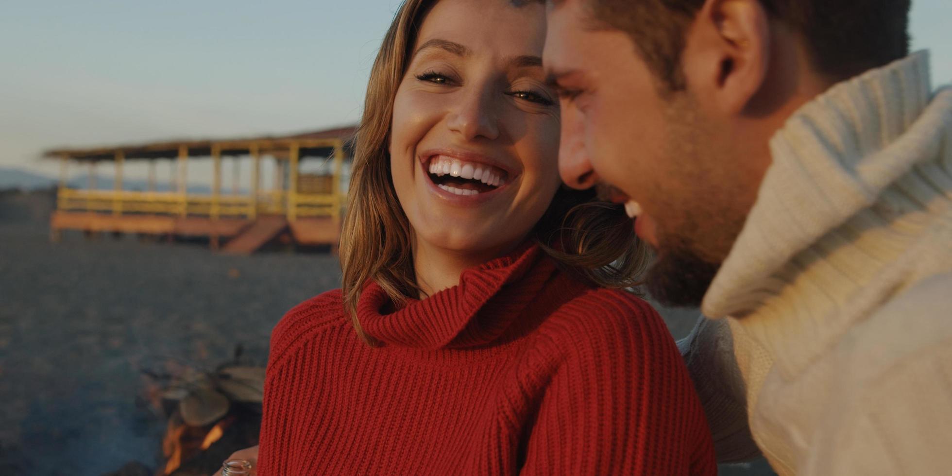 Loving Young Couple Sitting On The Beach beside Campfire drinking beer photo