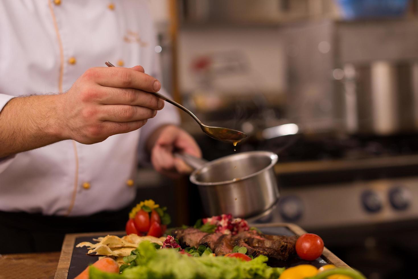 Chef finishing steak meat plate photo