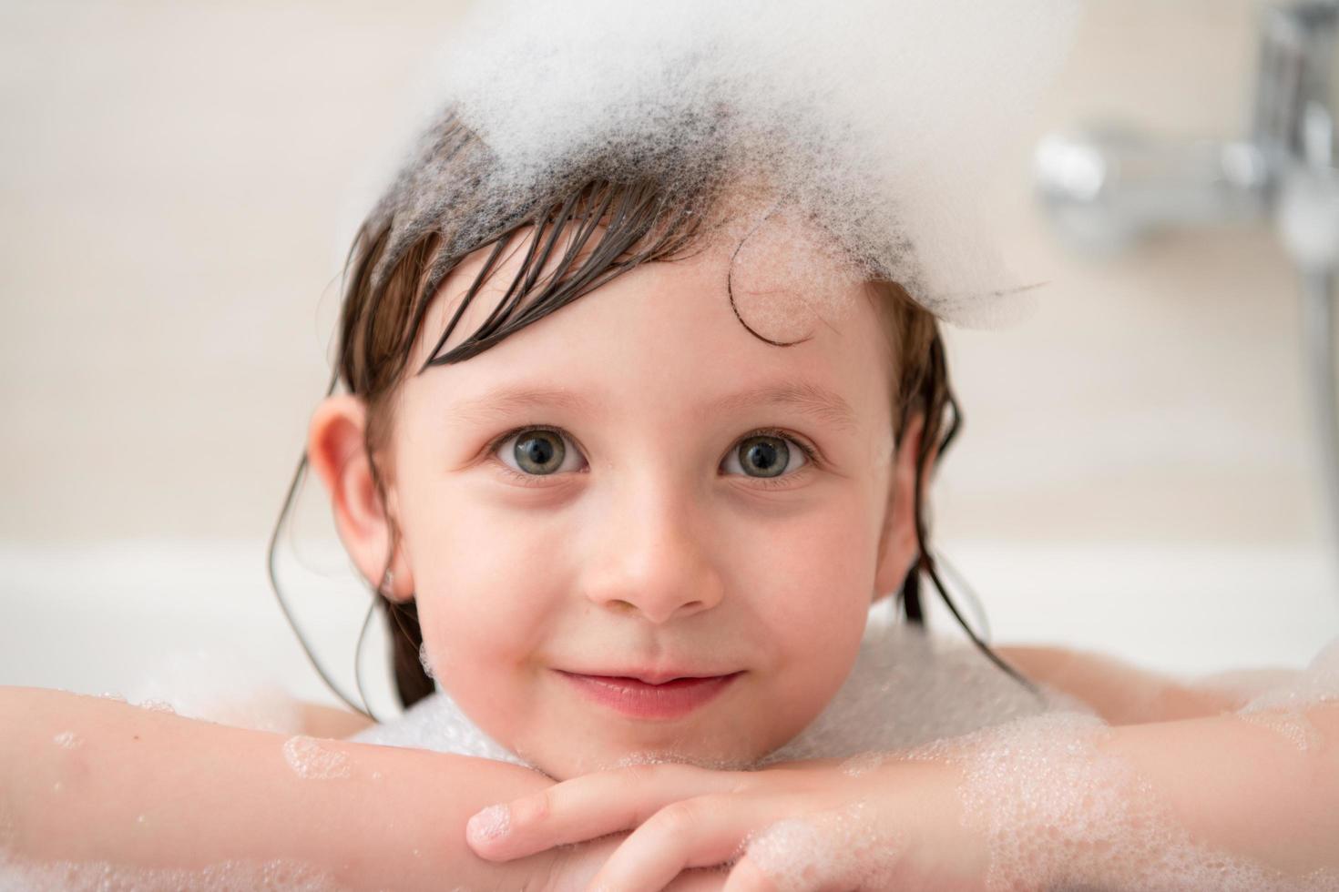 little girl in bath playing with foam photo