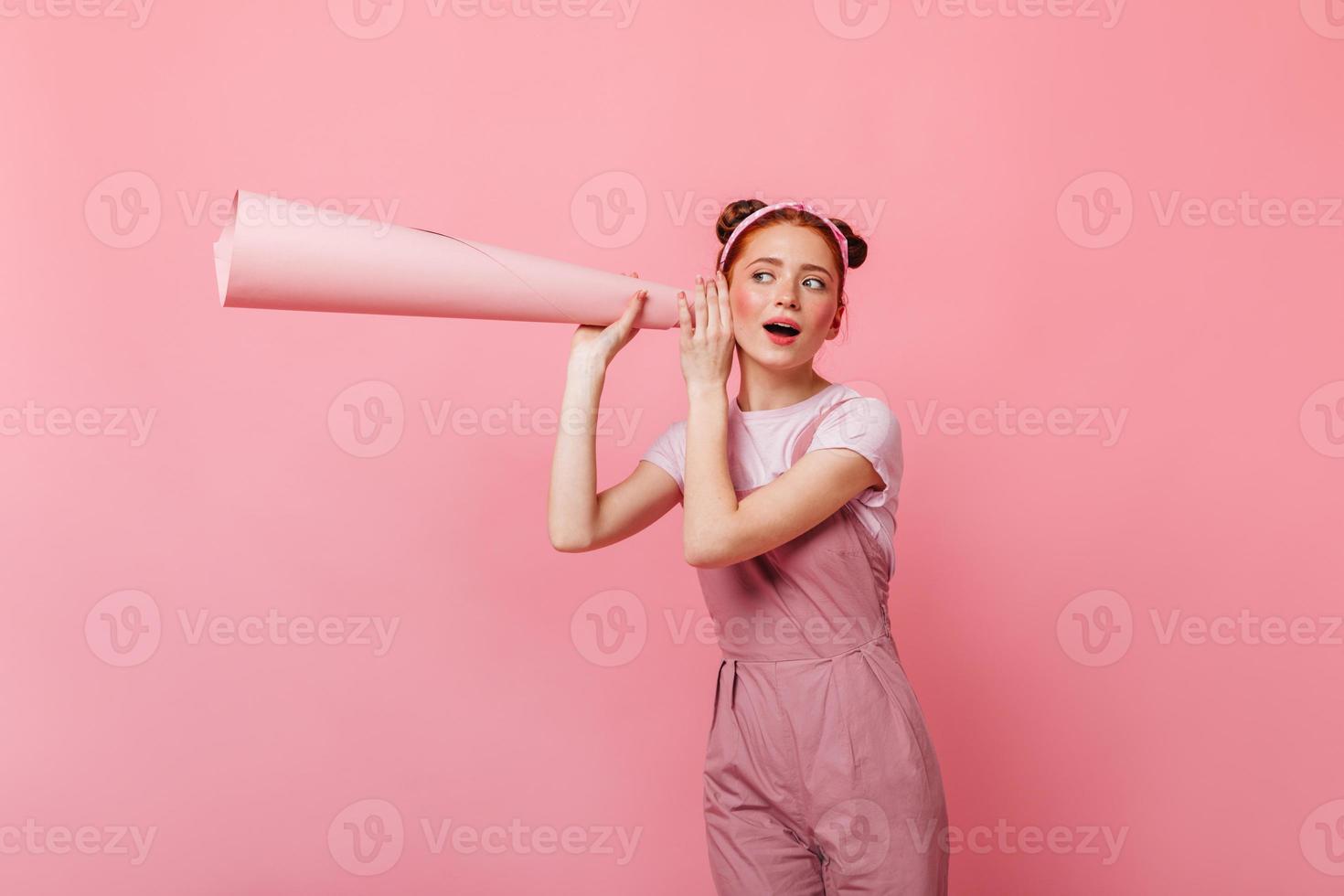 chica con bollos vestida con mono rosa bebe refrescos con fondo rosa foto