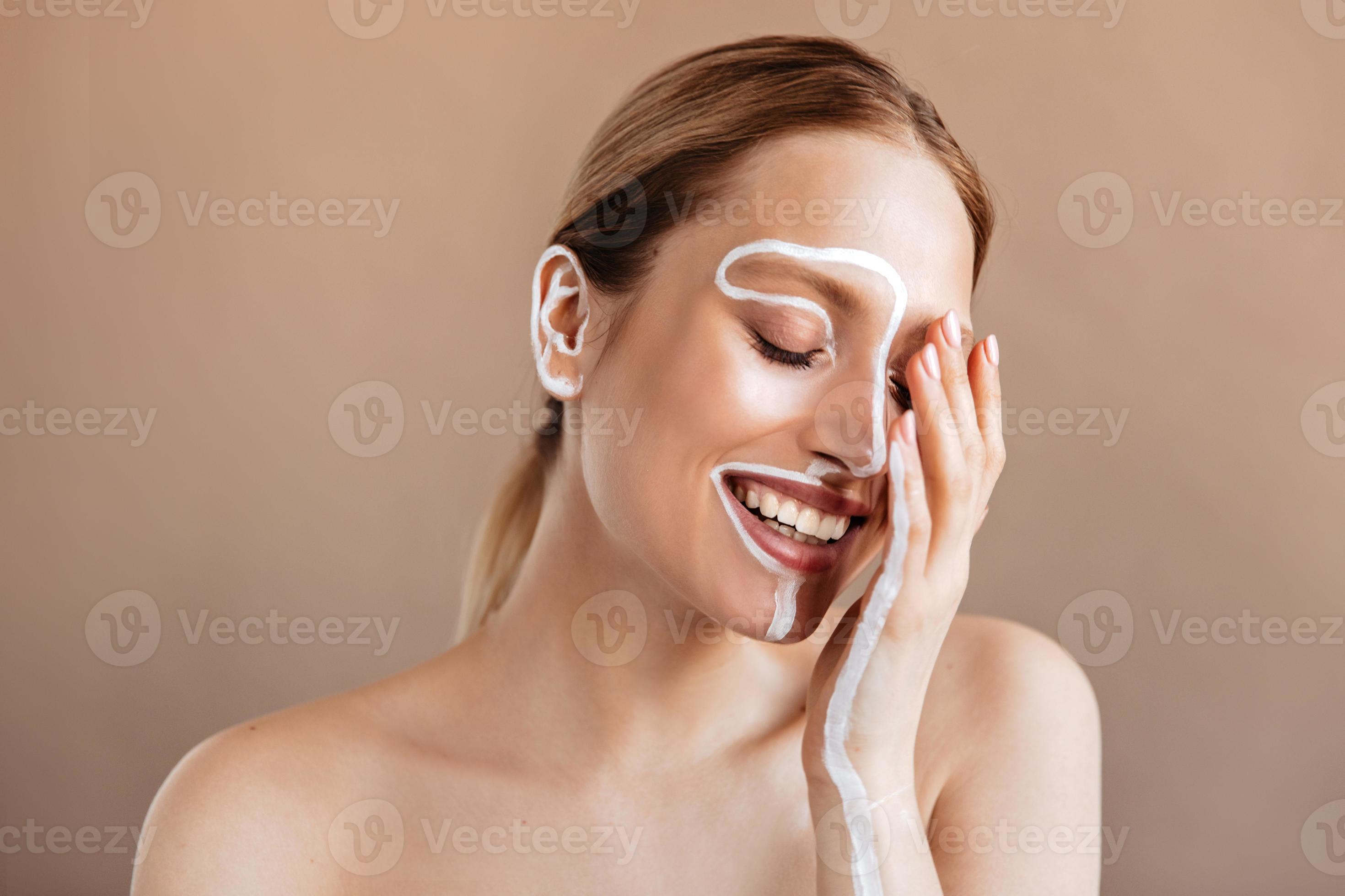 Positive girl with painted white line on face and hand laughs with