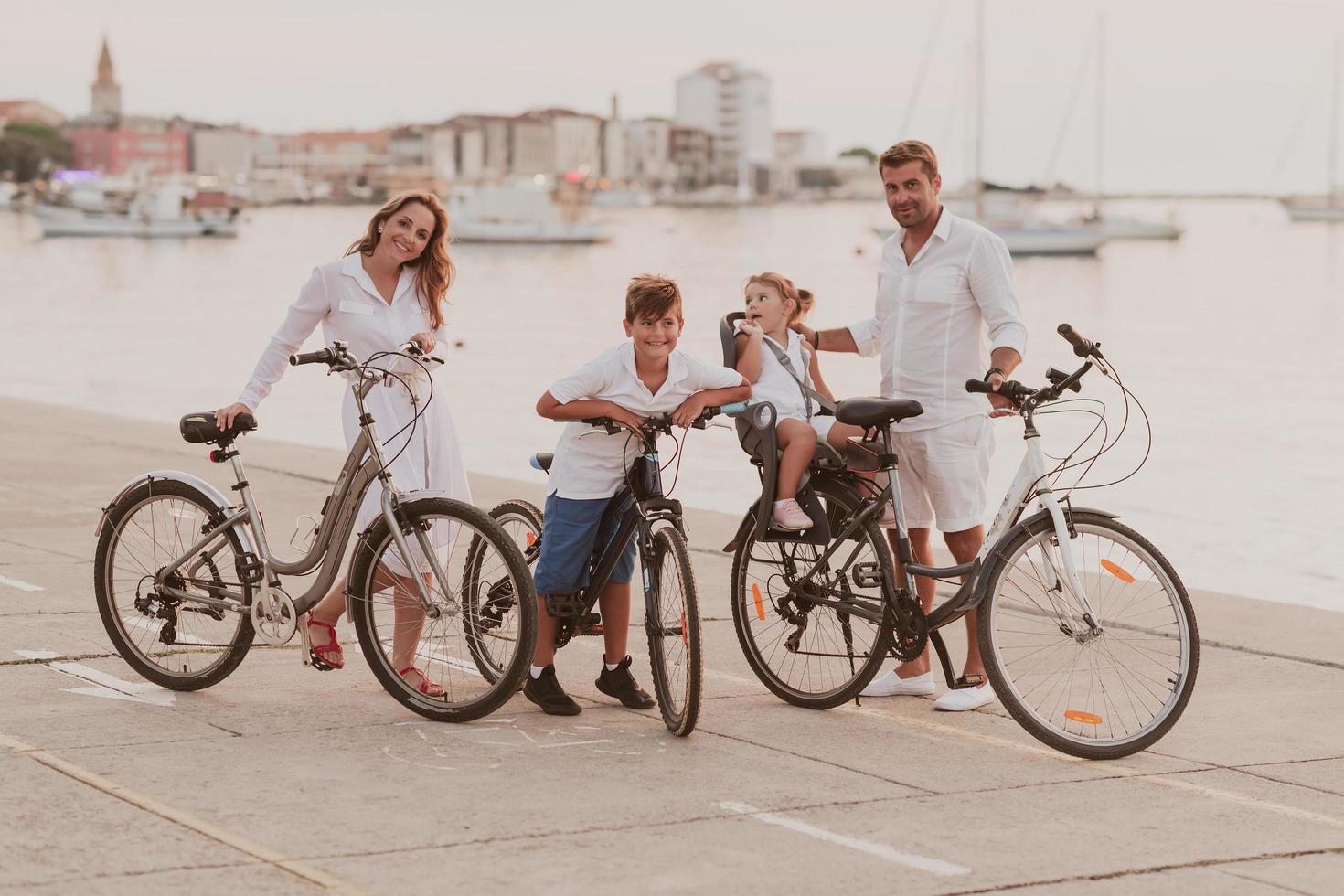 la familia feliz disfruta de una hermosa mañana junto al mar andando en bicicleta juntos y pasando tiempo juntos. el concepto de una familia feliz foto