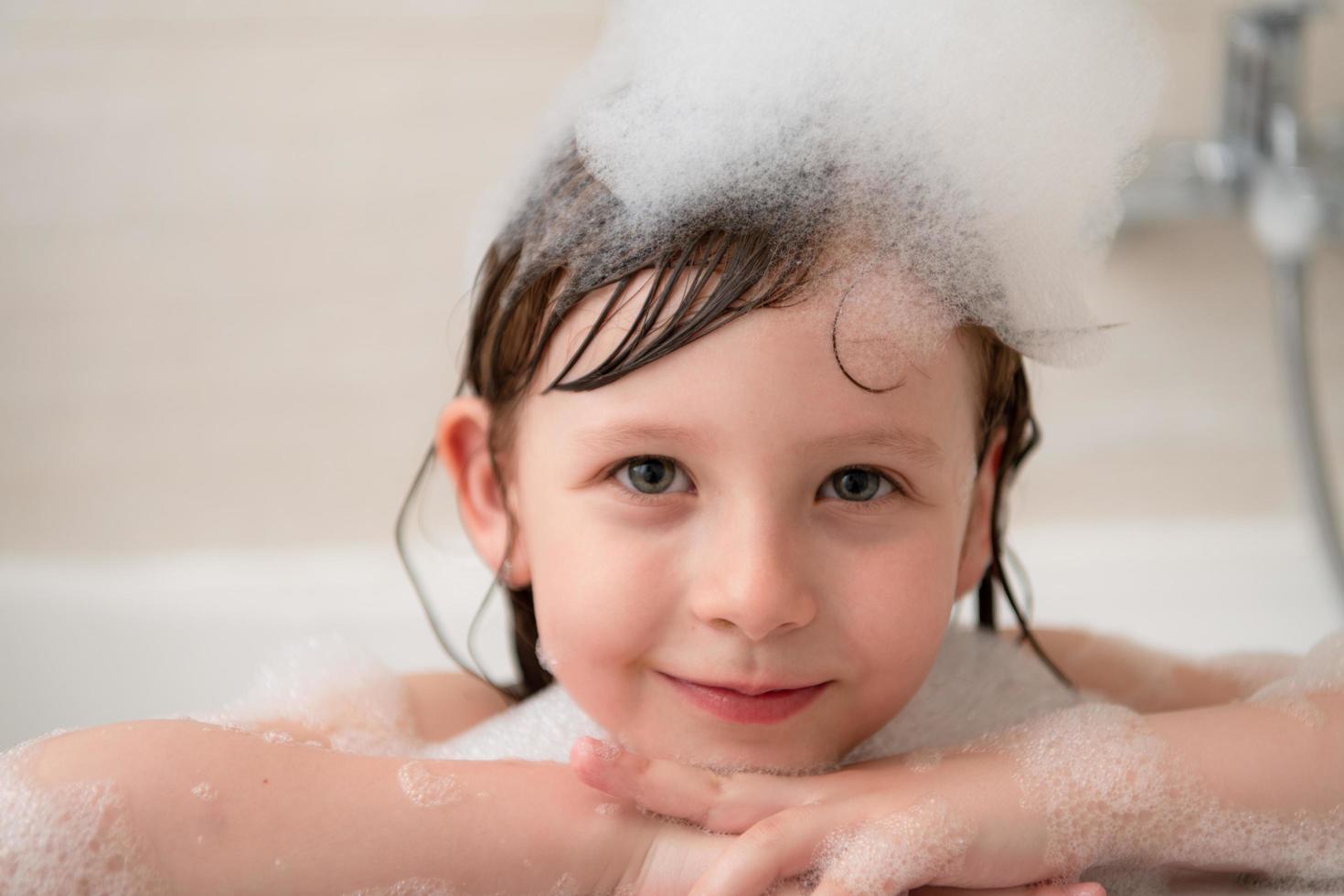 little girl in bath playing with foam photo