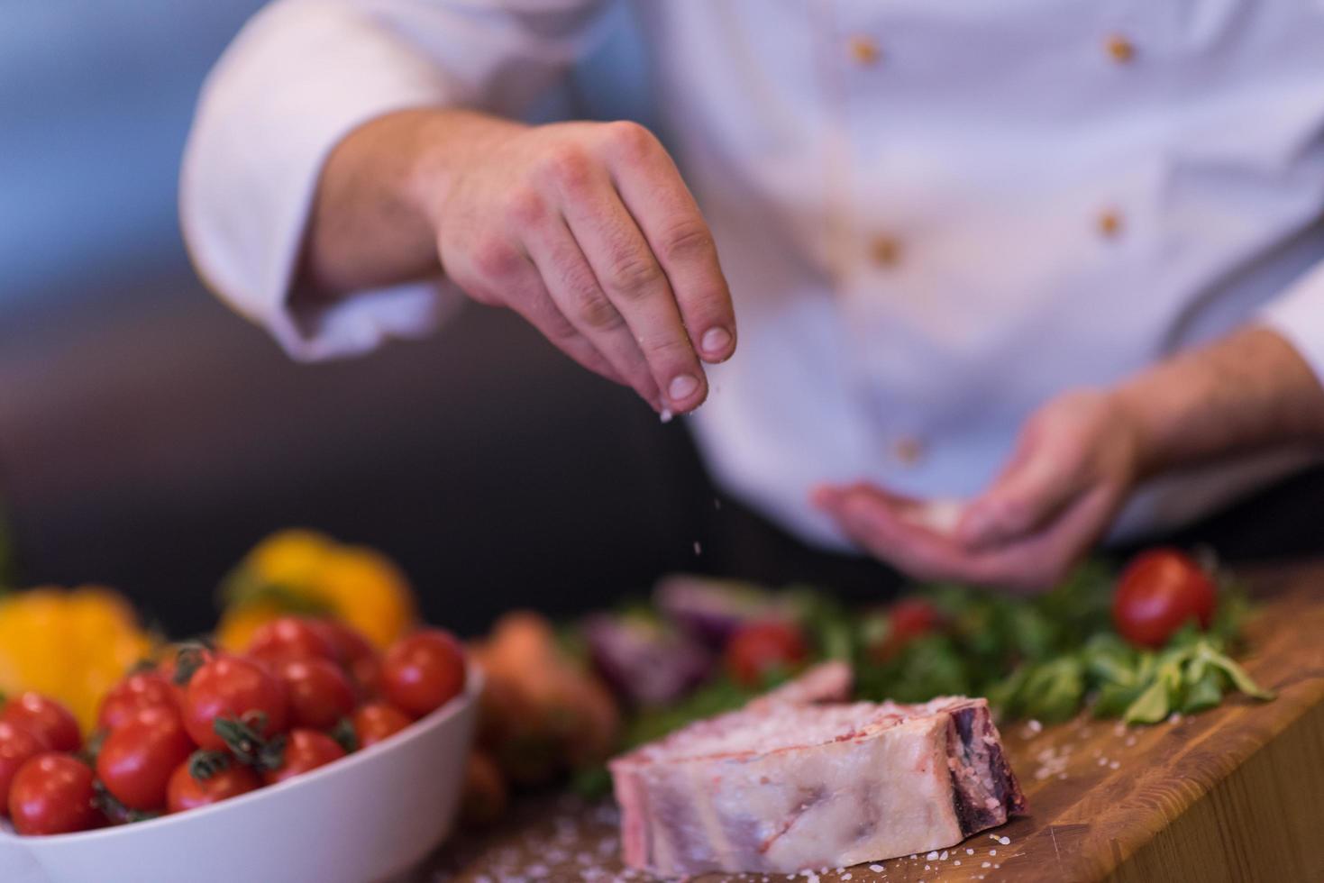 Chef putting salt on juicy slice of raw steak photo