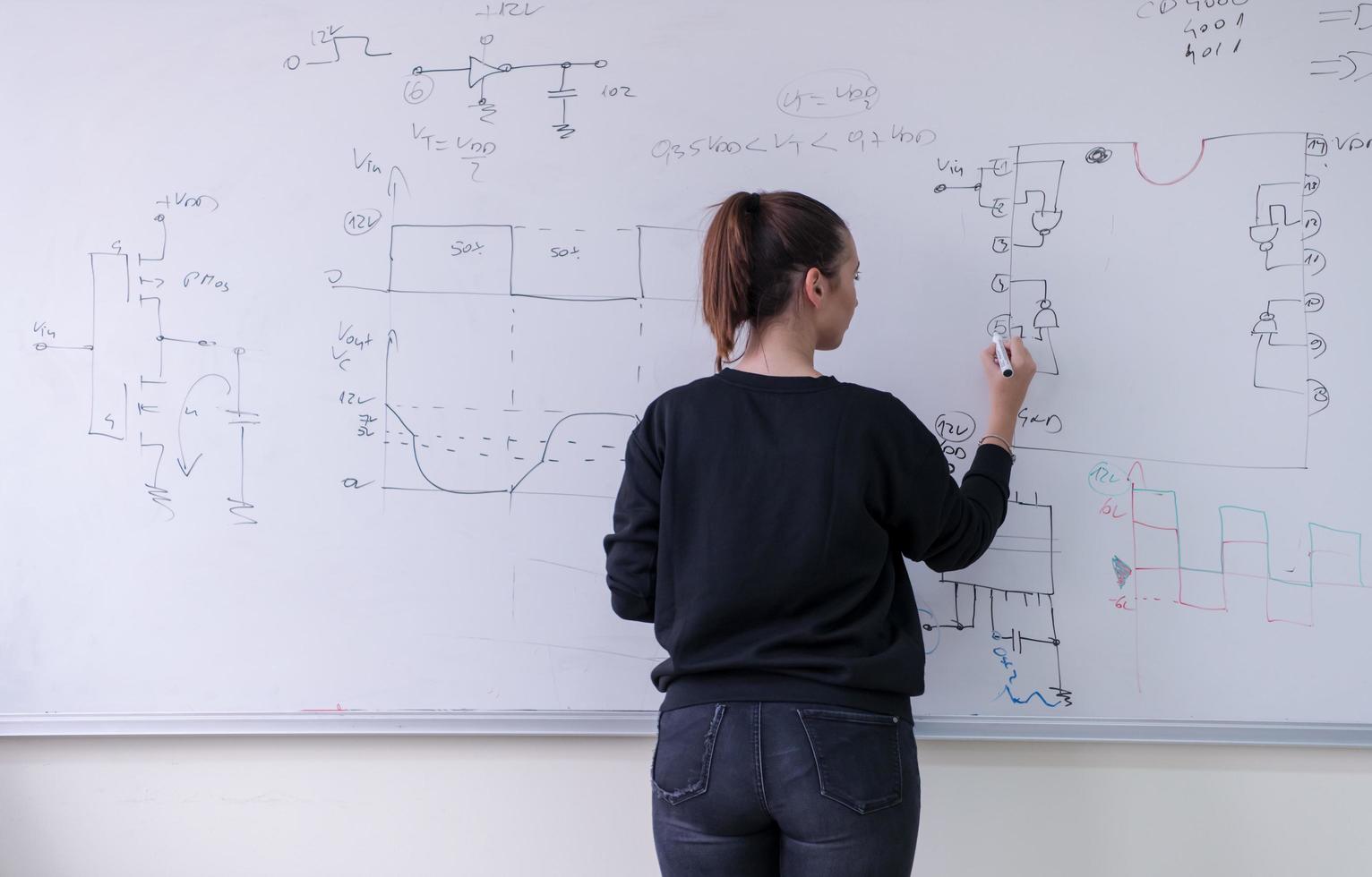 female student writing on board in classroom photo