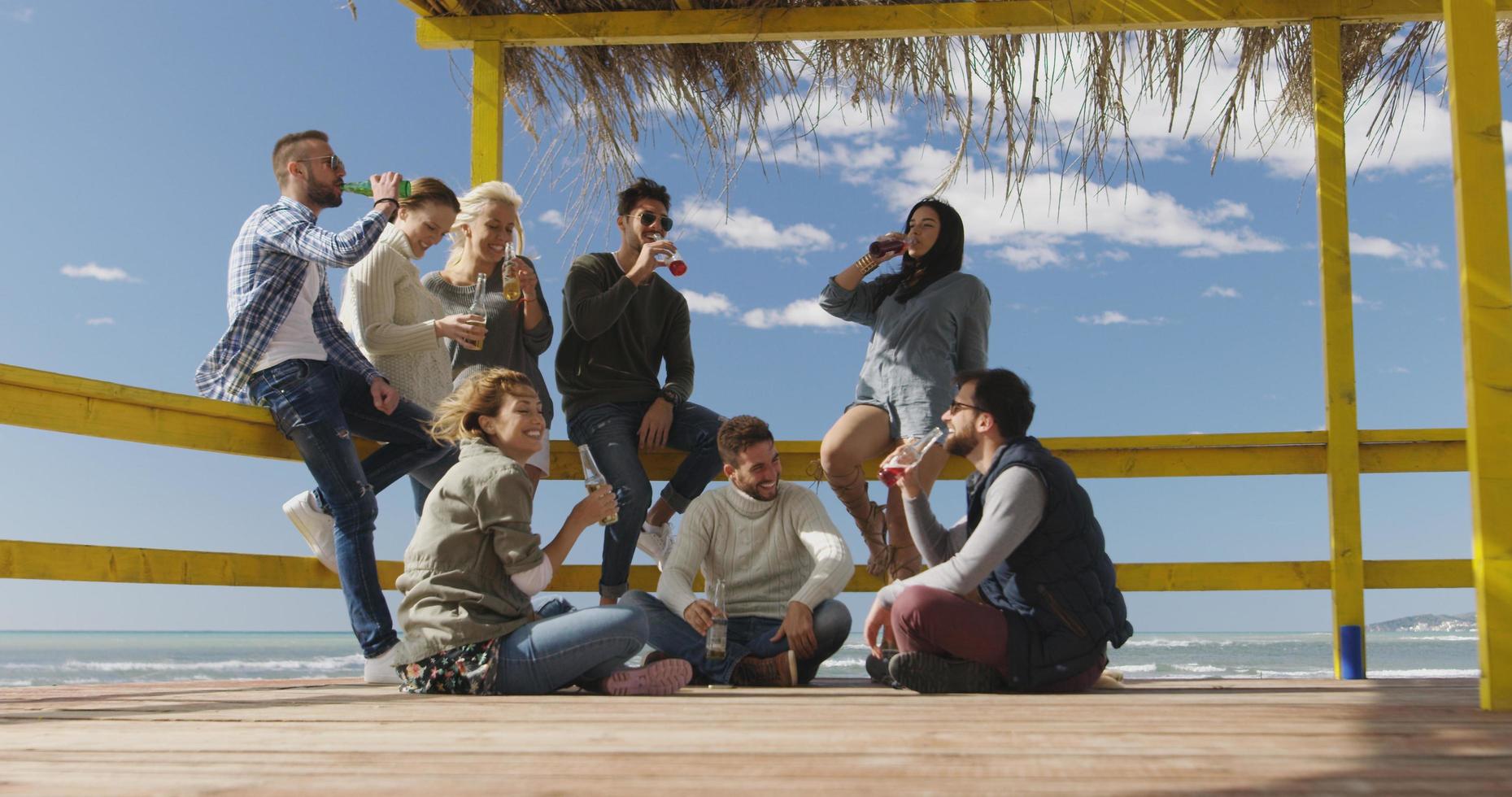 Group of friends having fun on autumn day at beach photo