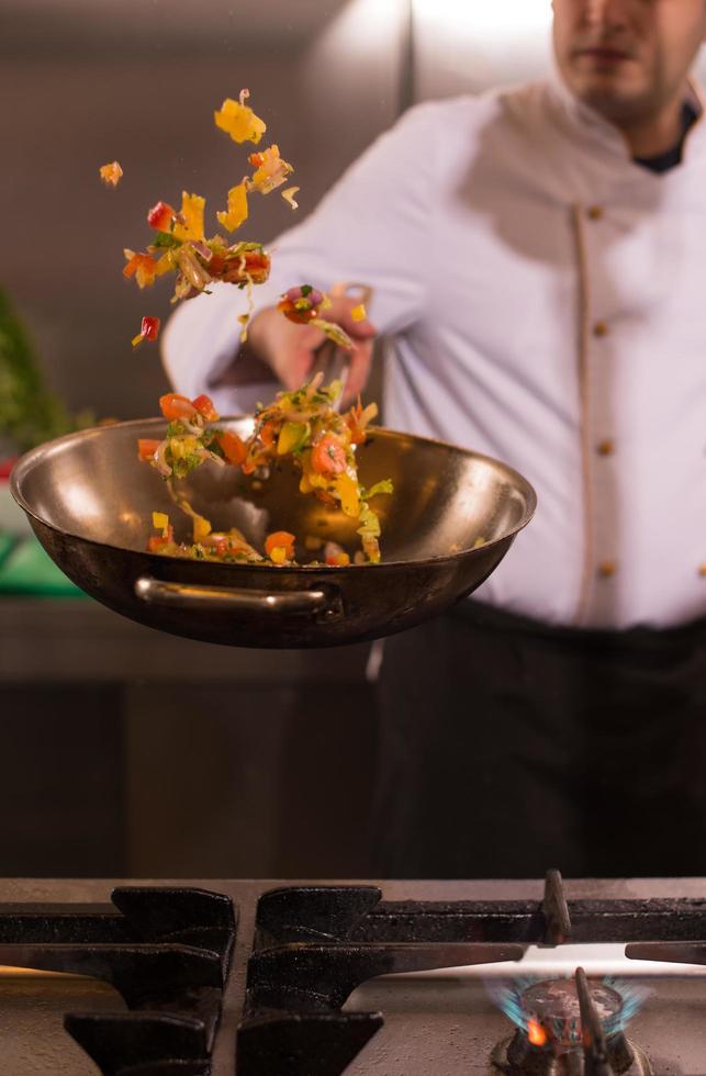 chef volteando verduras en wok foto