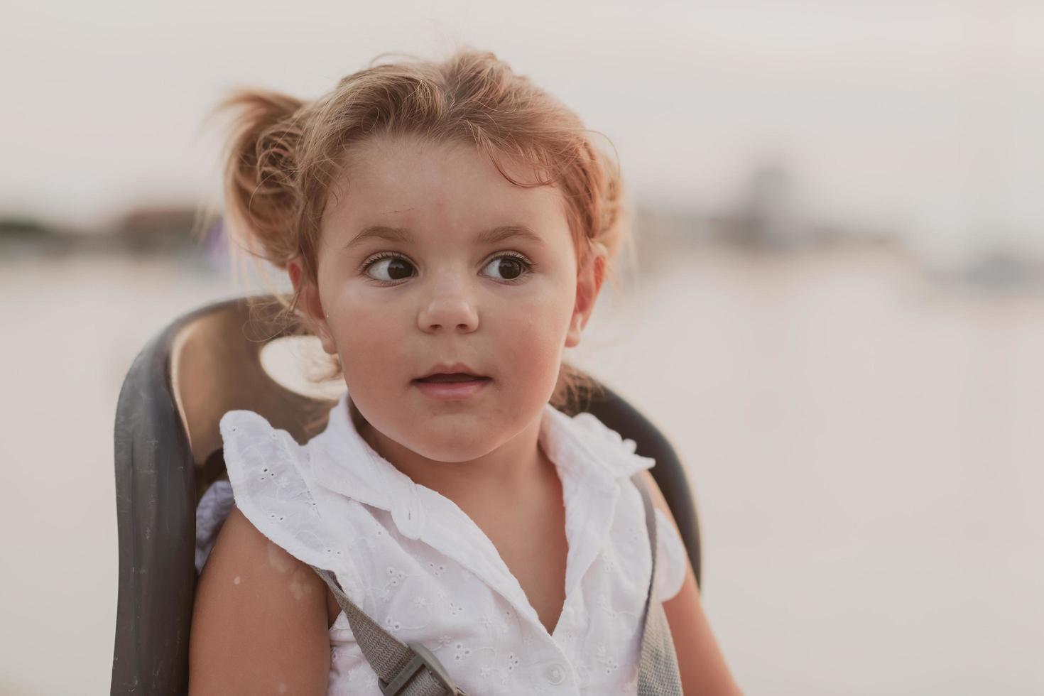 un retrato de una niña sonriente sentada en un asiento de bicicleta. enfoque selectivo foto