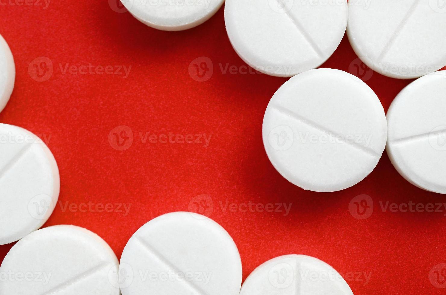 A few white tablets lie on a bright red background surface. Background image on medical and pharmaceutical topics photo
