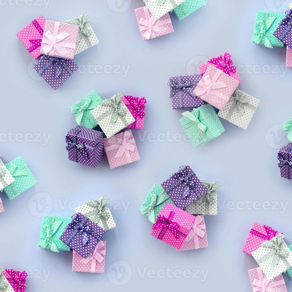Piles of a small colored gift boxes with ribbons lies on a violet background photo