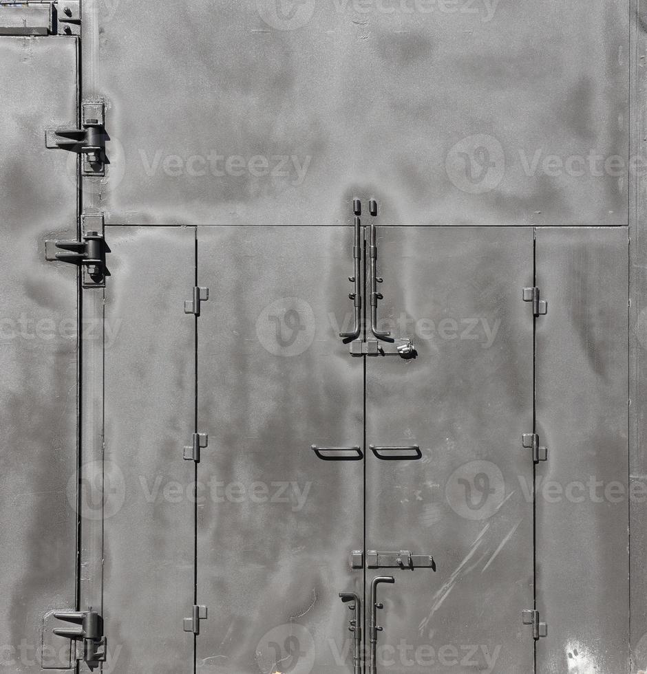 Black painted garage gates with door under the sunlight. Background texture or resource for 3d texturing photo