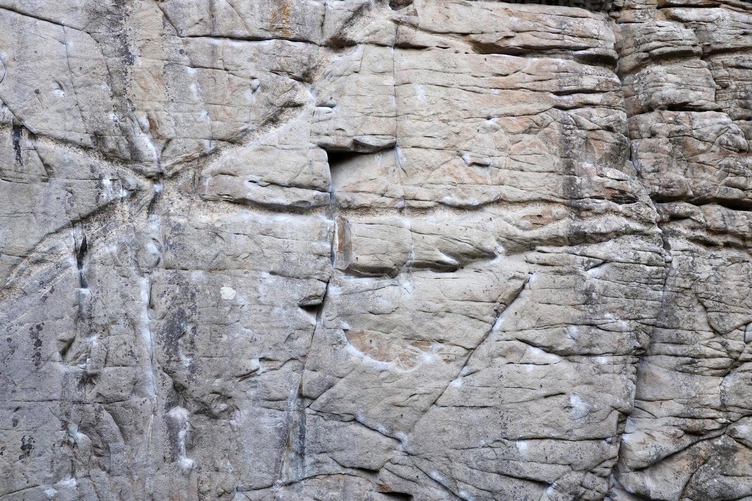 Light coarse natural rock stone background. Mining cliff rough front surface. Big limestone stack backdrop. Heavy grunge damaged granite block texture photo