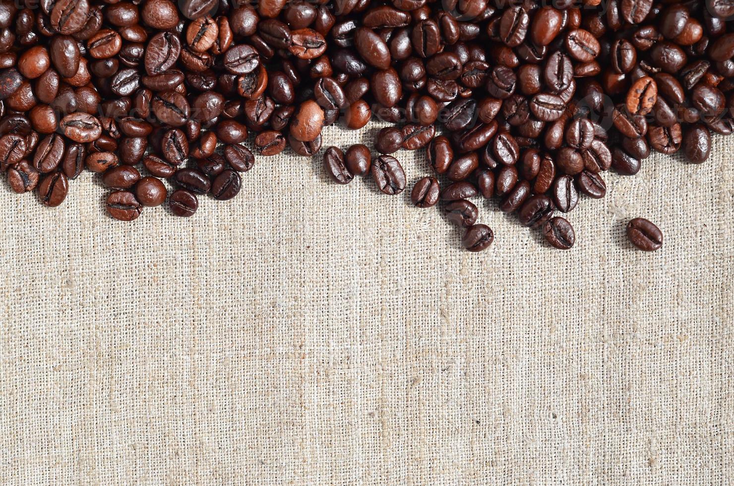Texture of a gray canvas made of old and coarse burlap with coffee beans on it photo