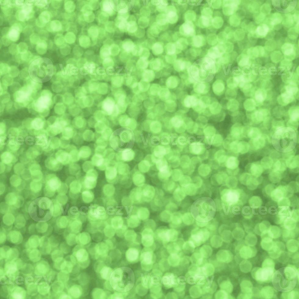 Blurred lime green decorative sequins. Background image with shiny bokeh lights from small elements photo