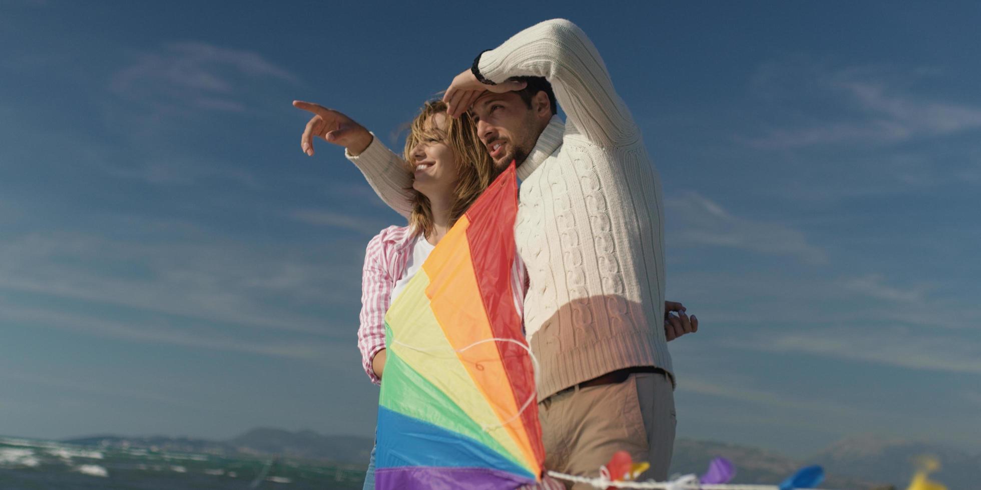 Happy couple having fun with kite on beach photo