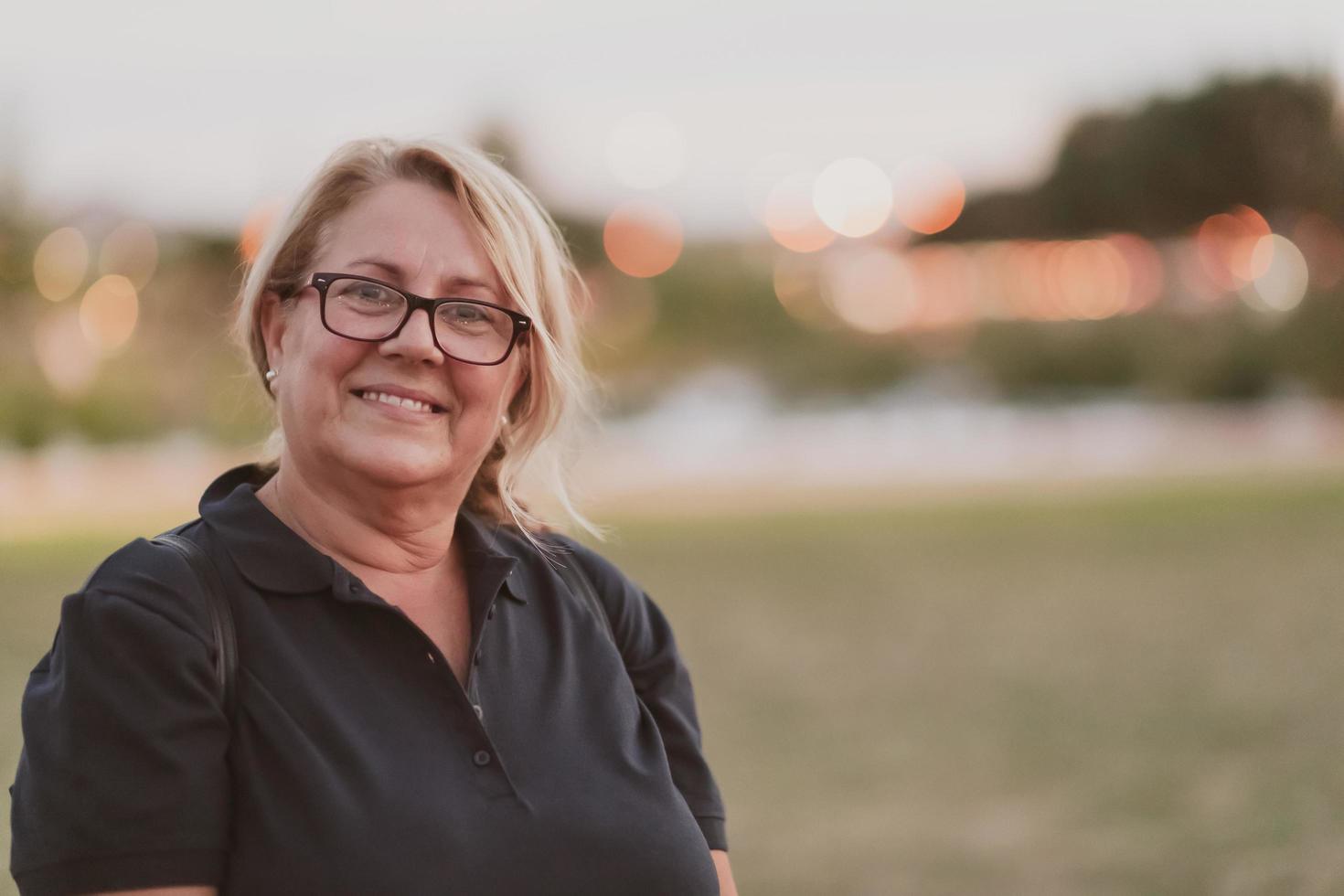 Portrait of an elderly woman with blonde hair and glasses on the beaches of the Mediterranean Sea at sunset. Selective focus photo