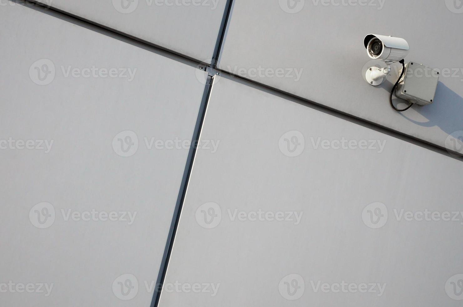 White surveillance camera built into the metal wall of the office building photo
