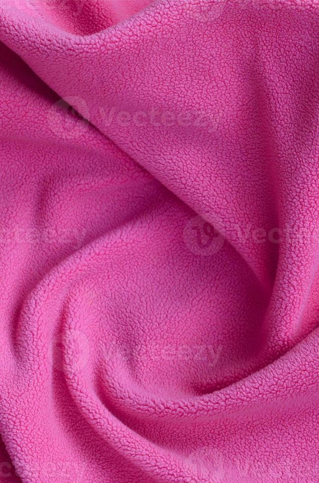 The blanket of furry pink fleece fabric. A background of light pink soft plush fleece material with a lot of relief folds photo