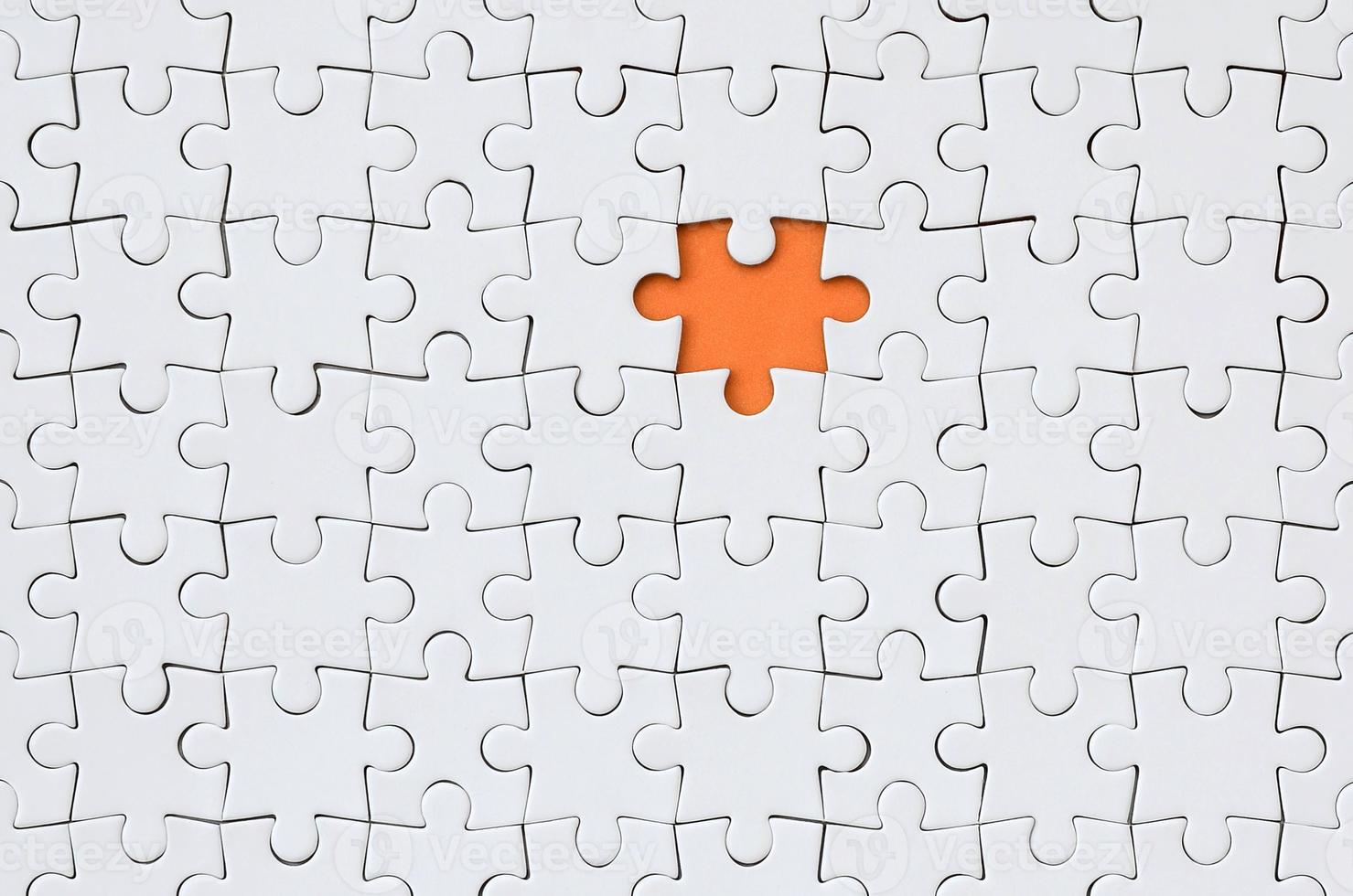 The texture of a white jigsaw puzzle in an assembled state with one missing element forming an orange space photo