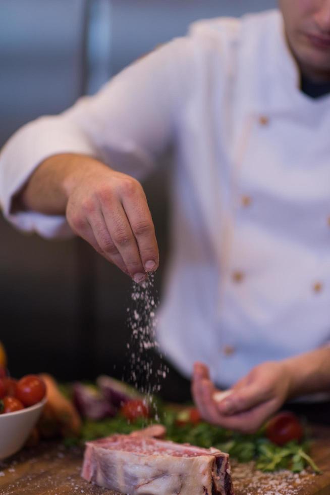 Chef putting salt on juicy slice of raw steak photo