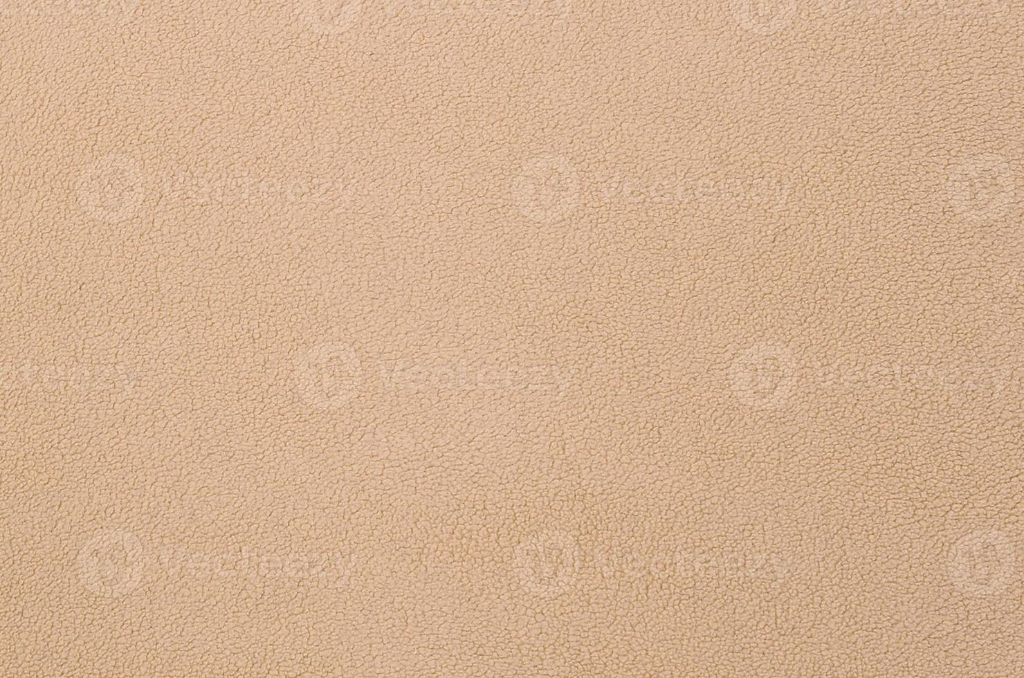 The blanket of furry orange fleece fabric. A background texture of light orange soft plush fleece material photo