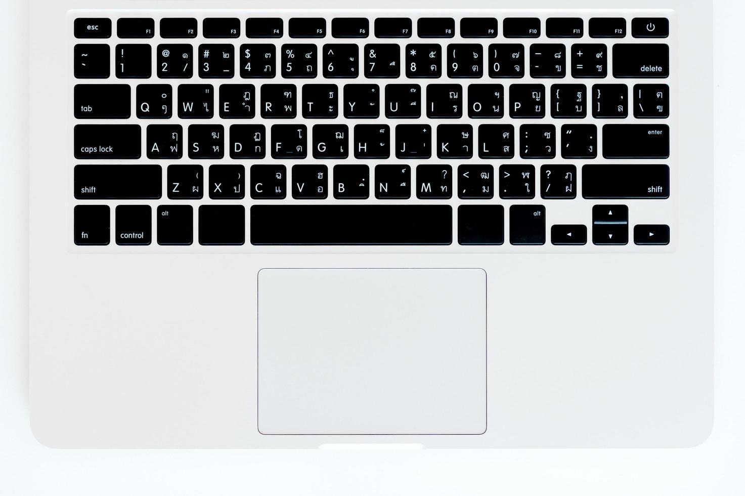 A laptop keyboard on a white wooden table. Top view photo