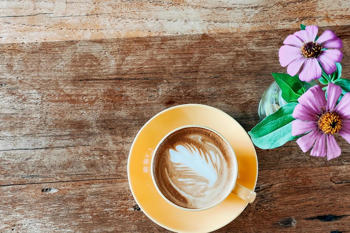 Top view of a latte art coffee on old wooden table. photo