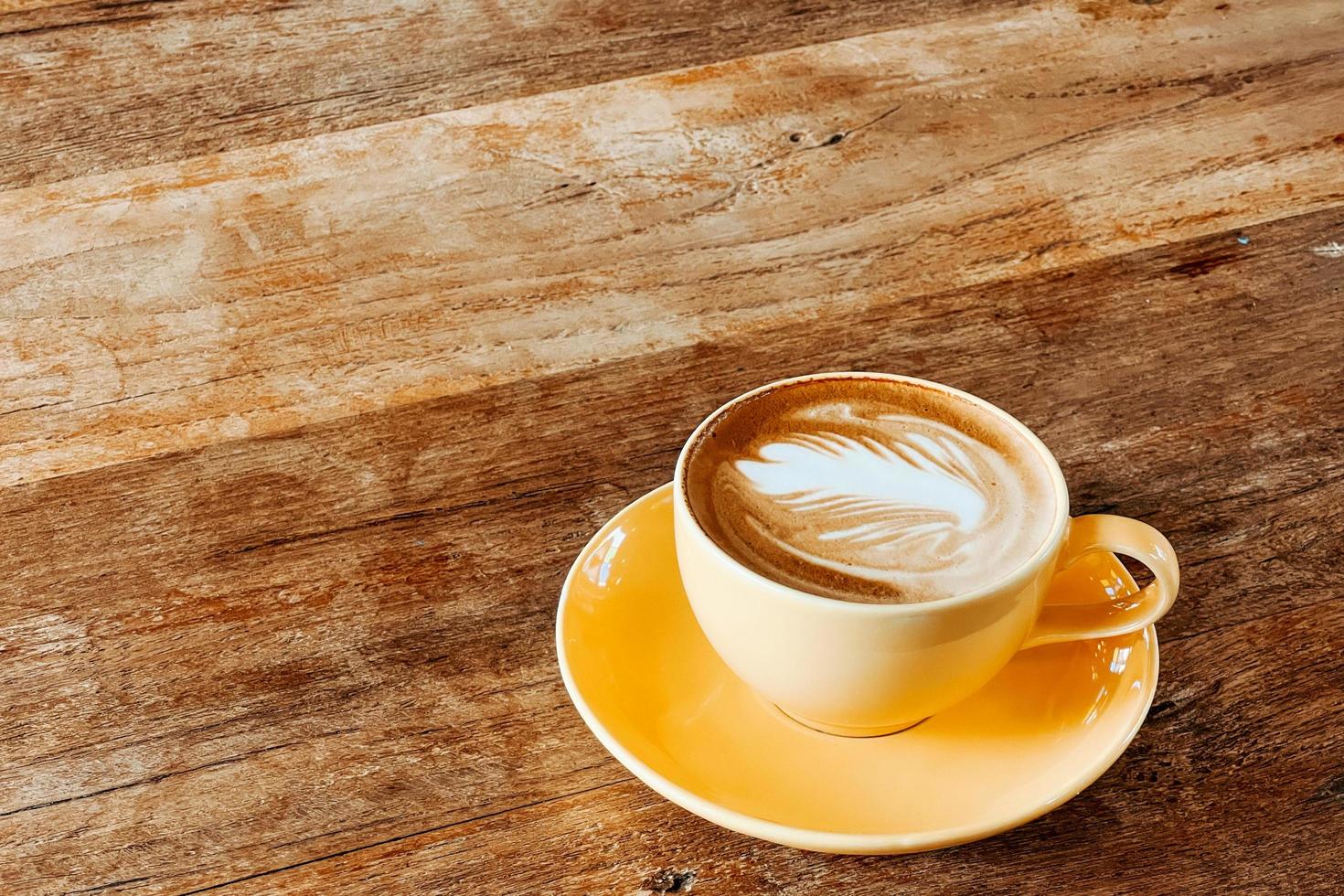 Top view of a latte art coffee on old wooden table. photo