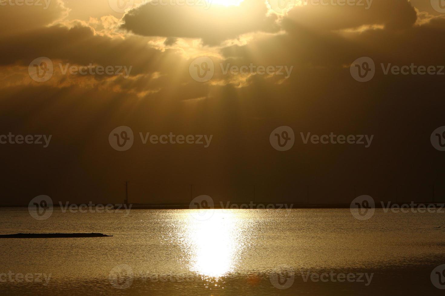 Sunrise on the shore of the Dead Sea in Israel. The sun rises from behind the mountains in Jordan. photo