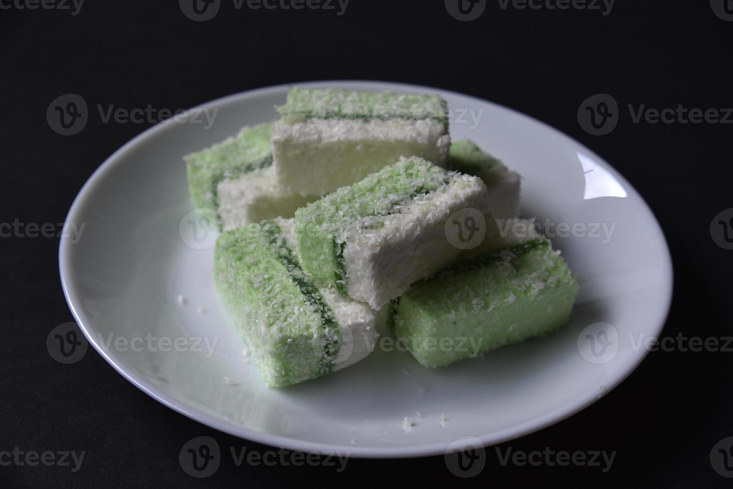 Delicious green and white pieces of pastille with coconut on a plate. Sweet pastille snack for tea. photo