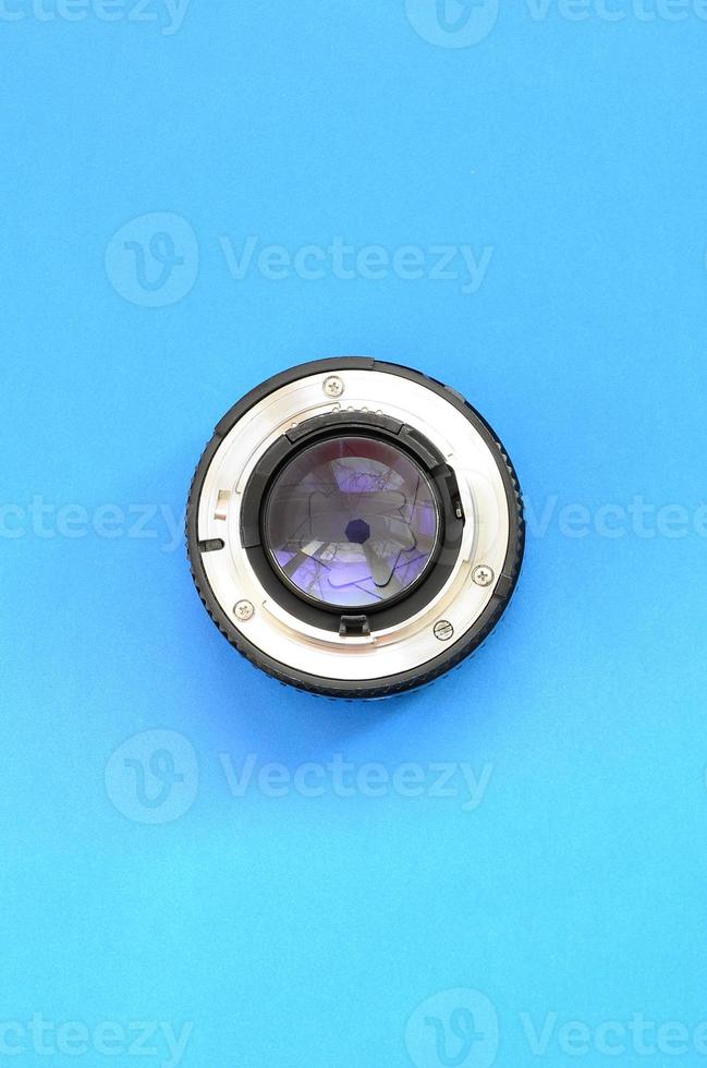 One photographic lense lie on a bright blue background. Space for text photo