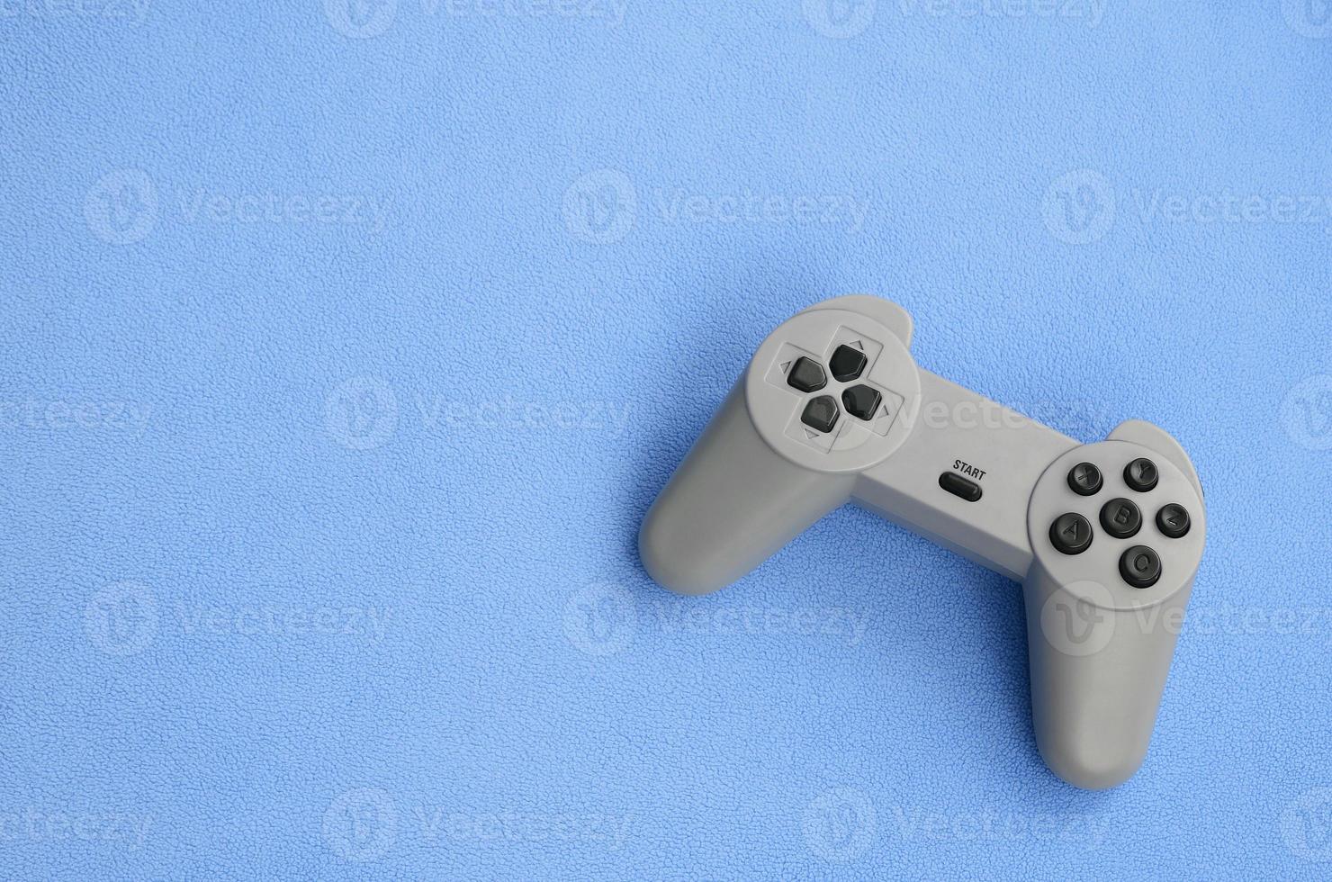 Playing games concept. Single pad joystick lies on the blanket of furry blue fleece fabric. Controller for video games on a background texture of light blue soft plush fleece material photo