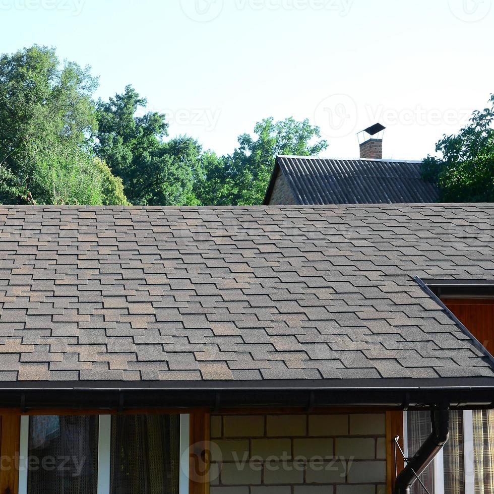 Modern roofing and decoration of chimneys. Flexible bitumen or slate shingles photo