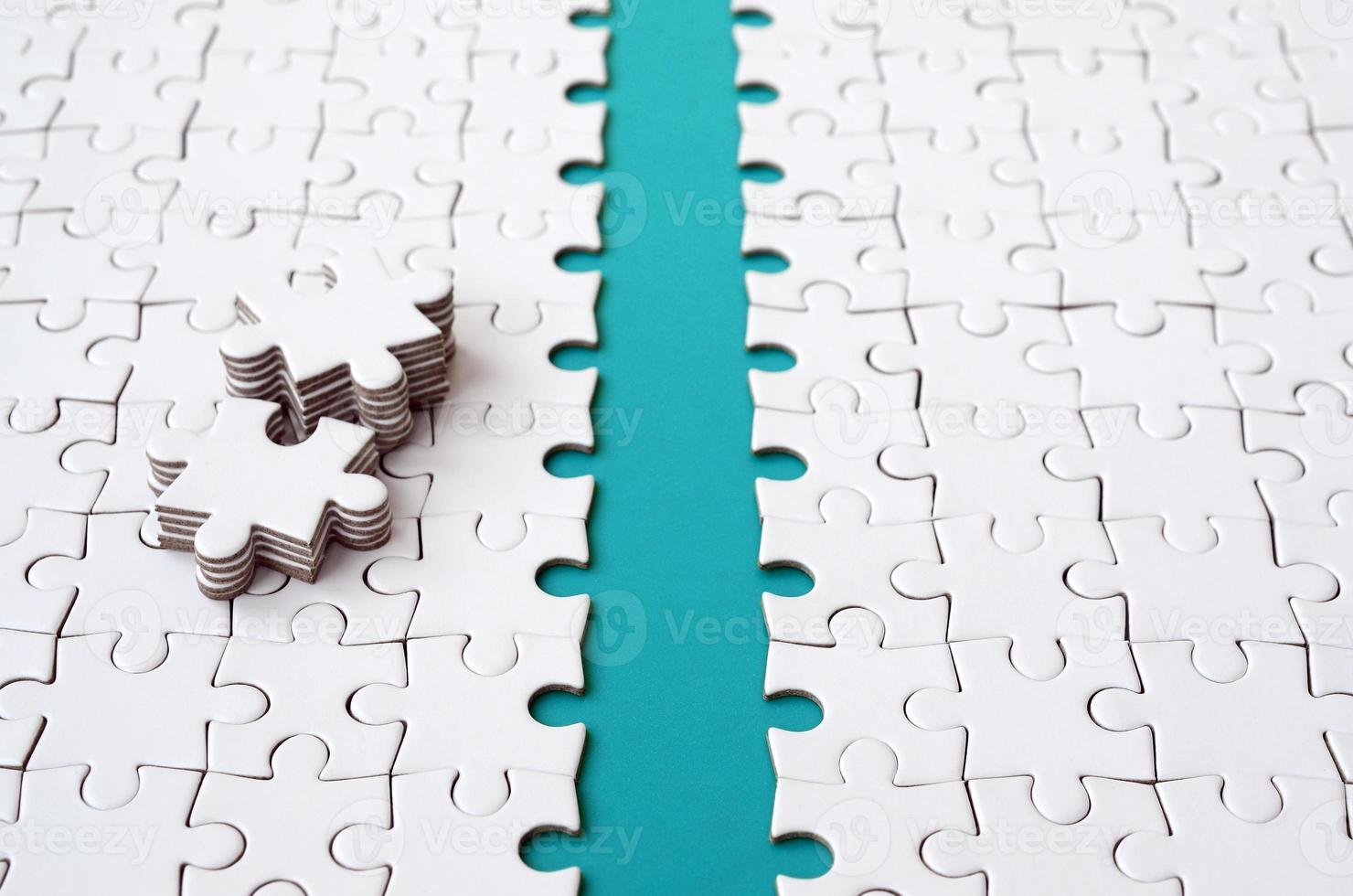 The blue path is laid on the platform of a white folded jigsaw puzzle. The missing elements of the puzzle are stacked nearby. Texture image with space for text photo