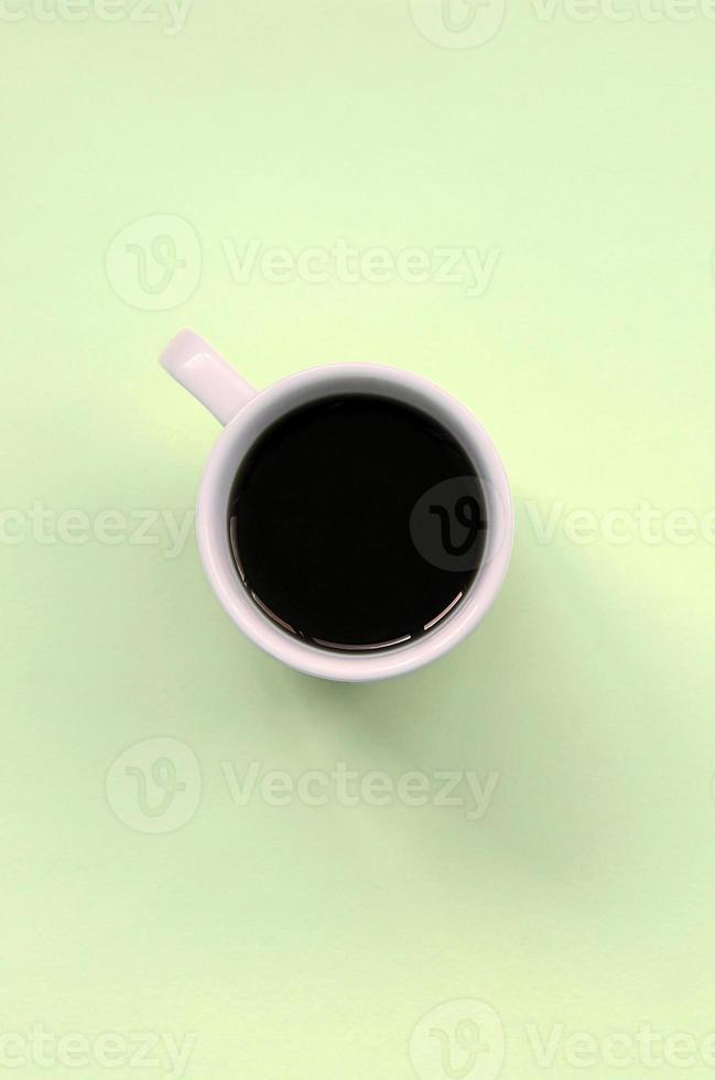 Small white coffee cup on texture background of fashion pastel lime color paper photo