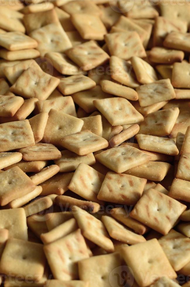 Background texture of small edible squares baked from dough and sprinkled with salt. A lot of salt cracker photo