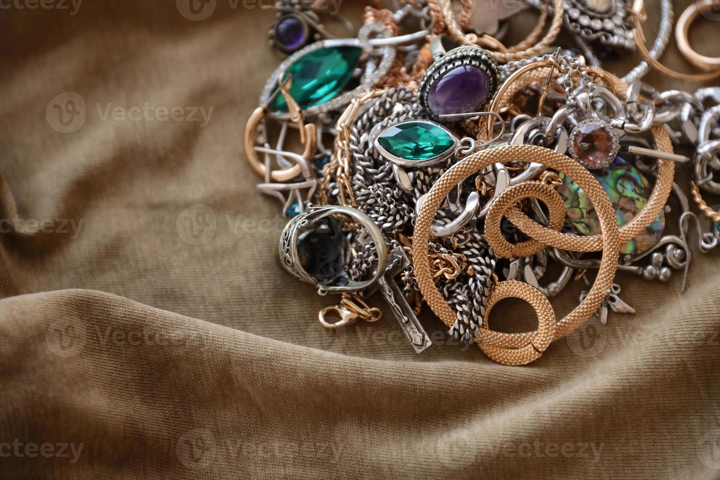Bunch of stolen jewelry on military uniform cloth fabric. Looting by Russian soldiers in the Ukrainian cities during the Russian attack on Ukraine. Marauders and looters photo