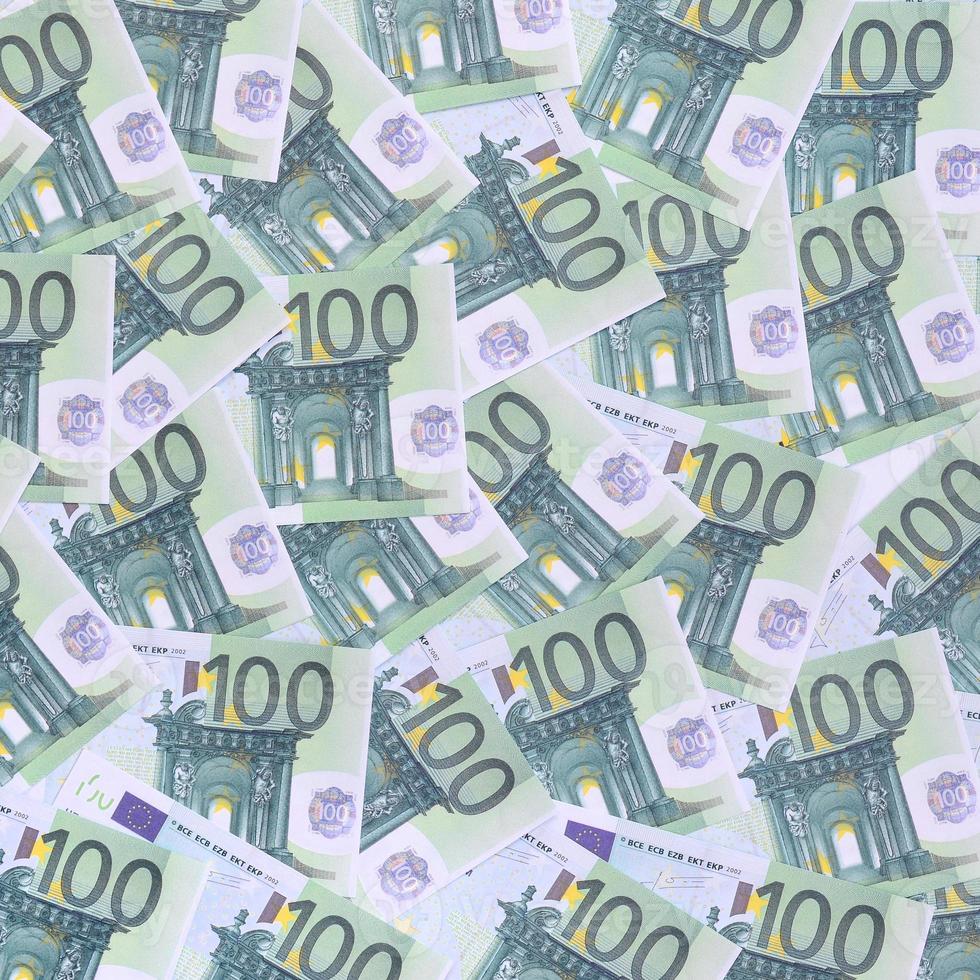 Background pattern of a set of green monetary denominations of 100 euros. A lot of money forms an infinite heap photo