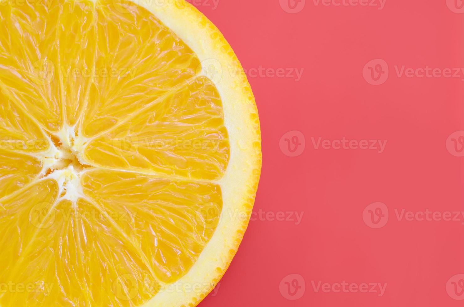 Top view of a one orange fruit slice on bright background in red color. A saturated citrus texture image photo