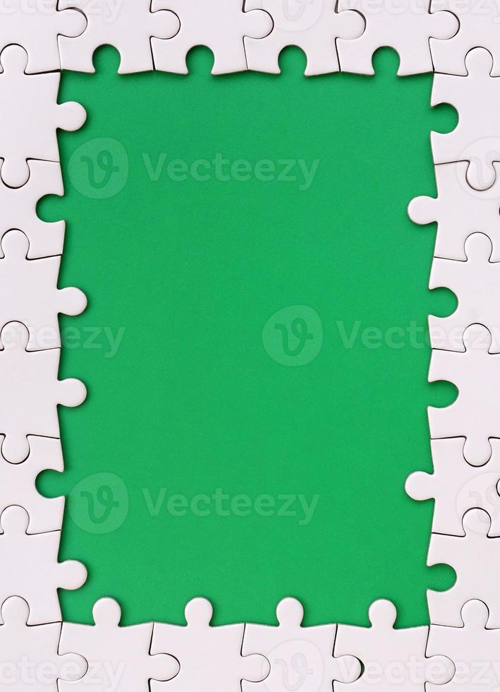Framing in the form of a rectangle, made of a white jigsaw puzzle around the green space photo