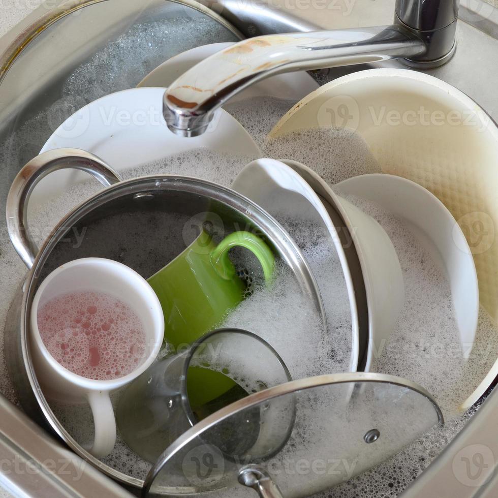 platos sucios y electrodomésticos de cocina sin lavar llenaron el fregadero de la cocina foto