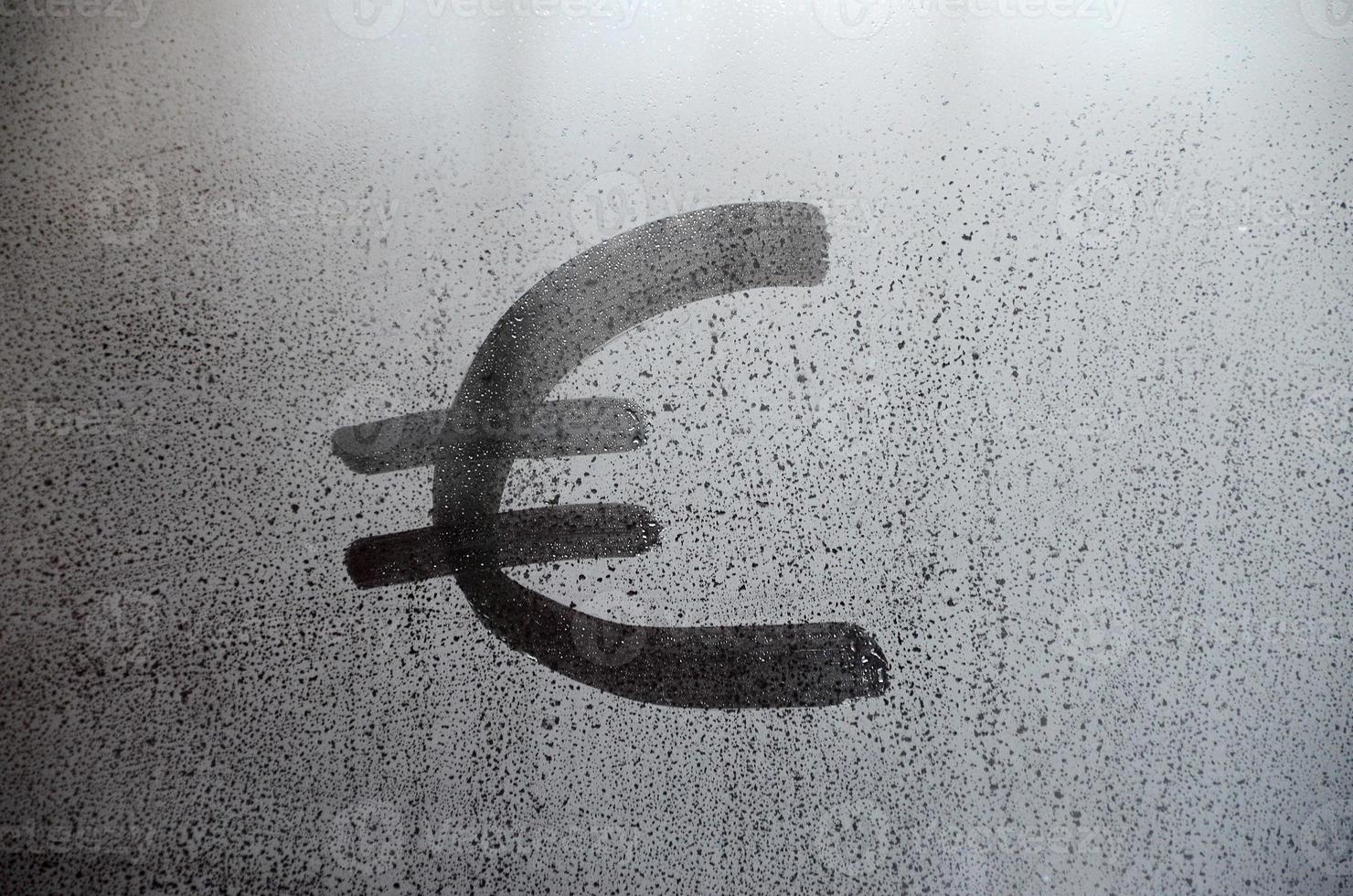 el símbolo de la moneda del euro en el vidrio empañado y sudoroso. imagen de fondo abstracto. concepto de moneda euro foto