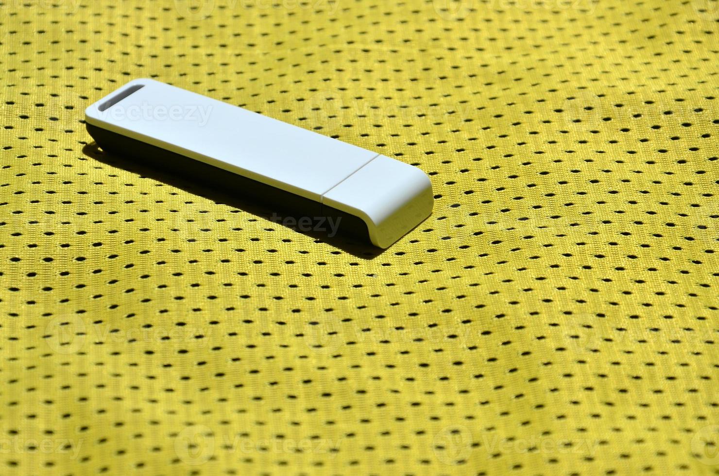 A modern portable USB wi-fi adapter is placed on the yellow sportswear made of polyester nylon fiber photo