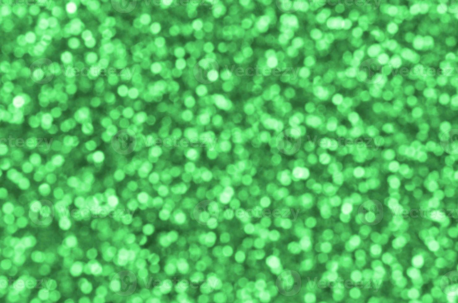 Blurred green decorative sequins. Background image with shiny bokeh lights from small elements photo