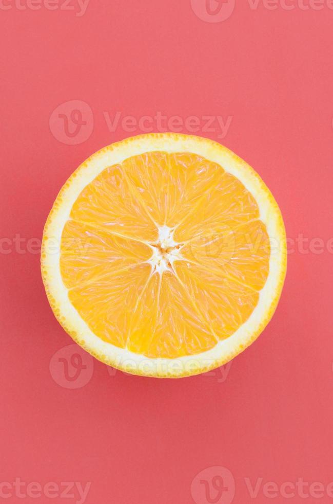 Top view of a one orange fruit slice on bright background in red color. A saturated citrus texture image photo