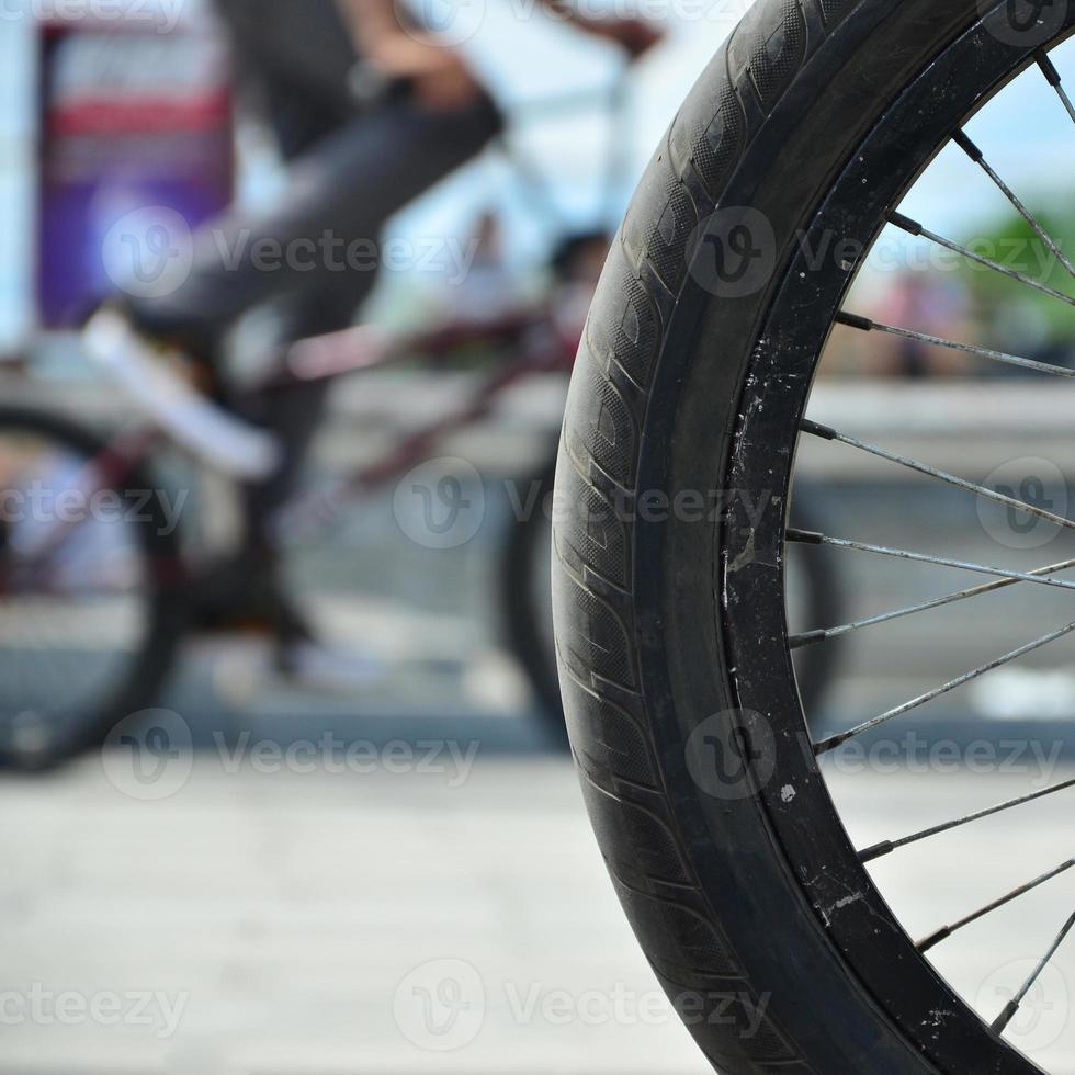 A BMX bike wheel against the backdrop of a blurred street with cycling riders. Extreme Sports Concept photo