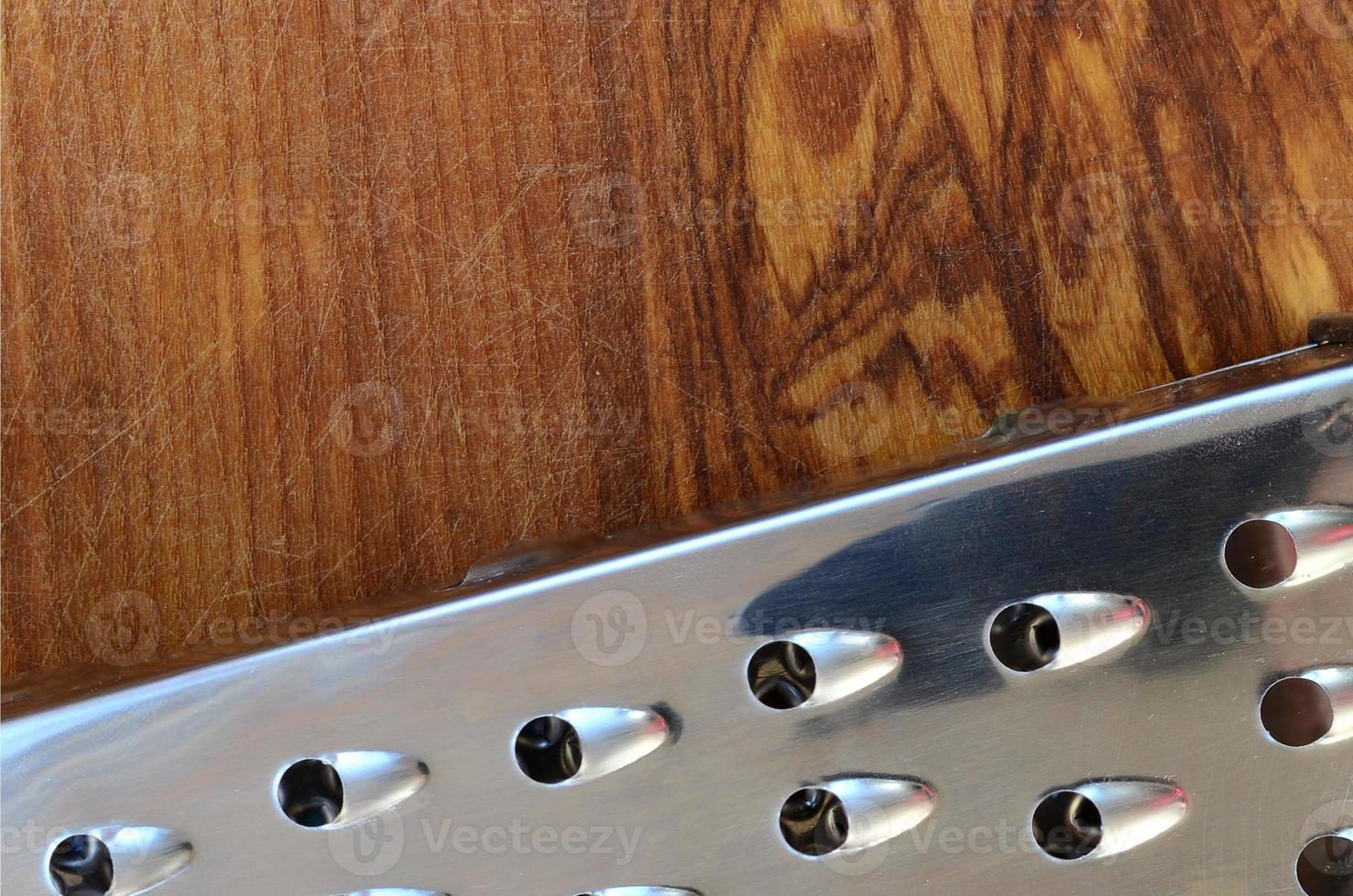 el rallador de cromo se encuentra en la tabla de cortar con muchas cicatrices del hacha y el cuchillo. imagen de fondo para recetas de cocina foto