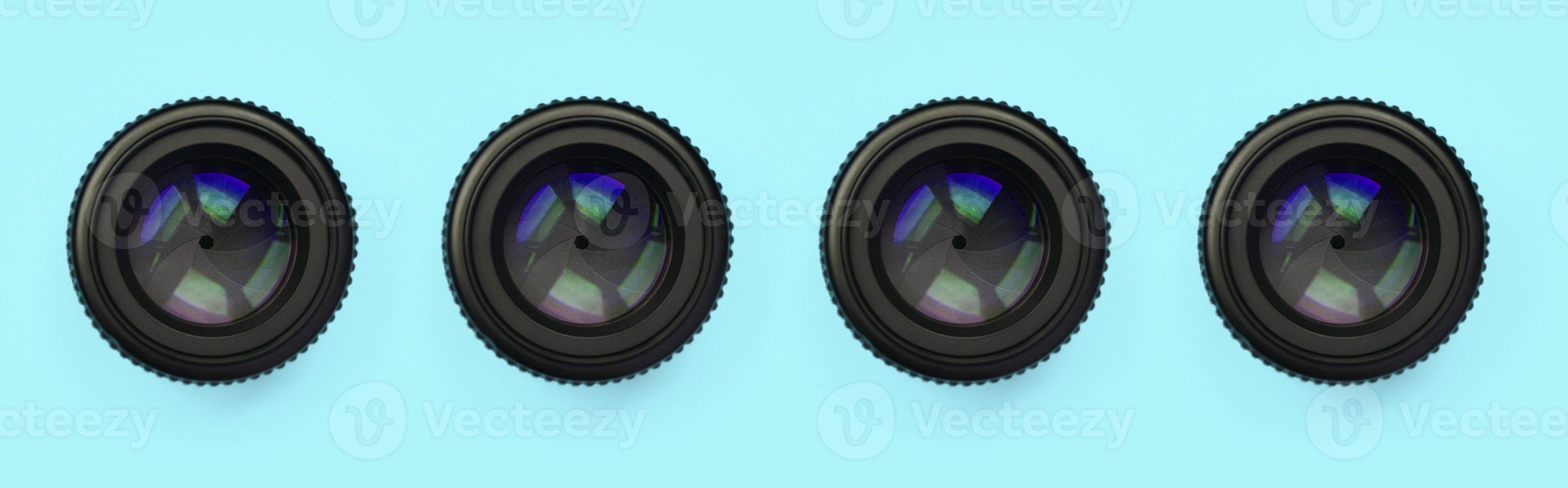 A few camera lenses with a closed aperture lie on texture background of fashion pastel blue color paper photo