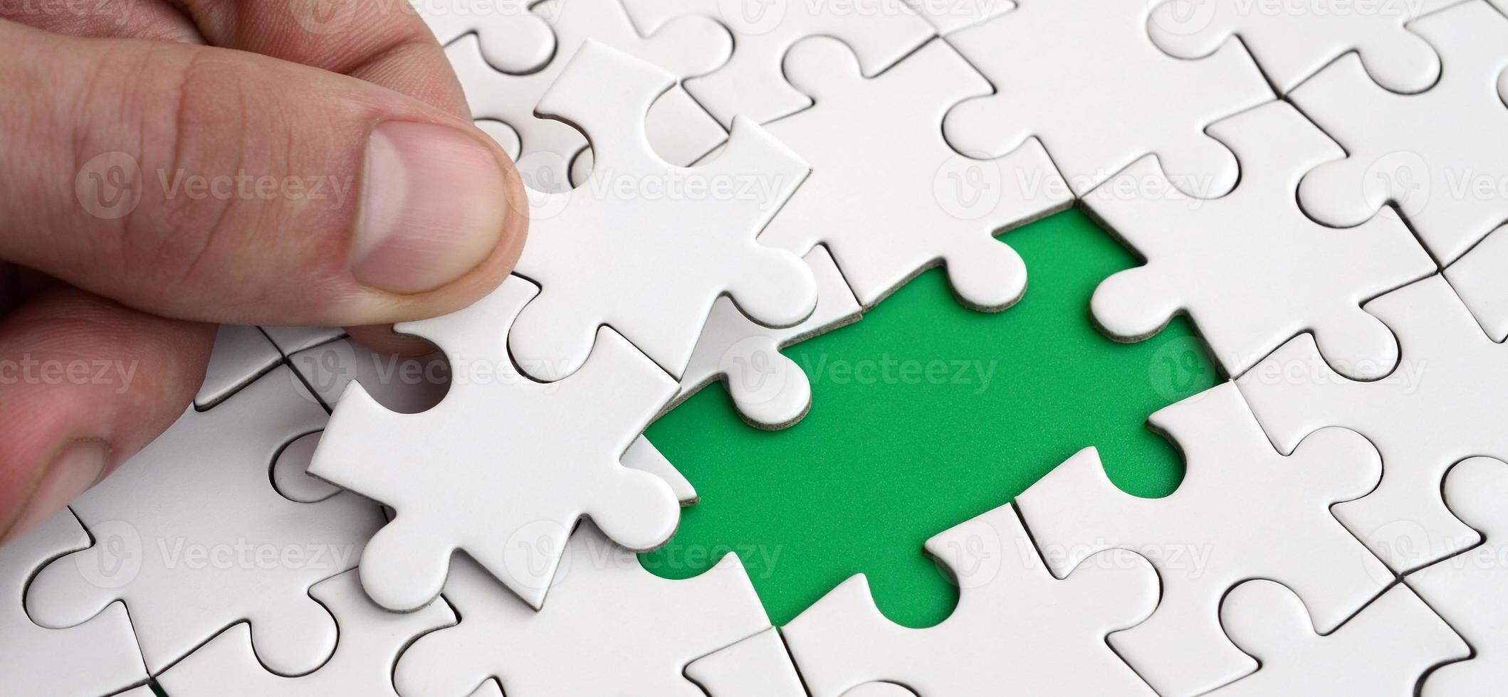 The human hand fills the last missing elements of the surface from the jigsaw puzzle. The concept of the completion of the initiated cases photo